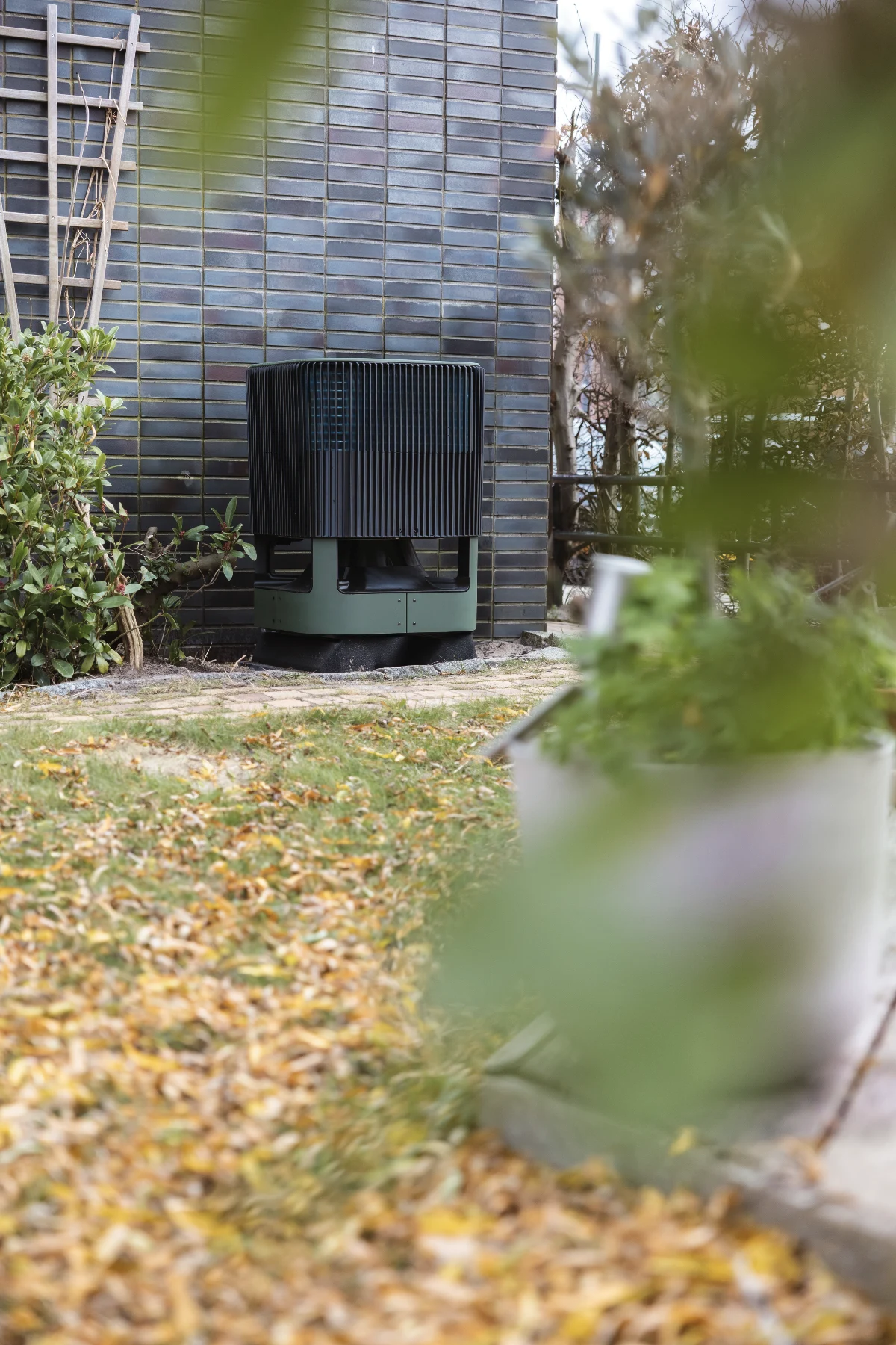De Whspr staat in een herfsttuin tussen het groen en de gevallen bladeren